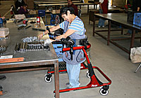 Movement disorders don’t stop this woman from assembling parts in a warehouse space in a Rifton gait trainer