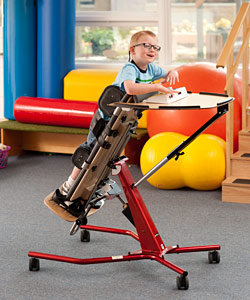 A young boy smiles as he stands upright in his assistive technology stander