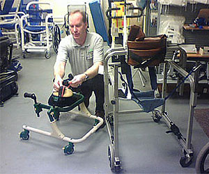 Don Hoerman adjusts a strap on a Rifton gait trainer in the Equipment Restoration Center at NEAT