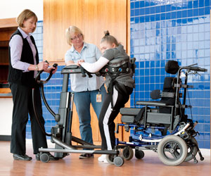 Two therapists help a young girl walk in the TRAM during a mobility product demo