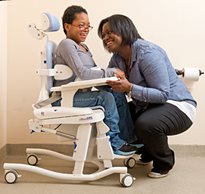 A caregiver properly positions a young girl with special needs in a hygiene and toileting system from Rifton