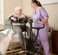A therapist uses a Rifton TRAM to safely handle a patient moving them from a seated position on a hospital bed to a standing and mobile position.