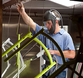 A worker at Rifton spray coats an adaptive bicycle made in their facility in the USA