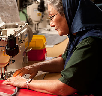 A pile of red fabric pieces used for adaptive devices is sewn by a professional at the Rifton manufacturing facility in the USA
