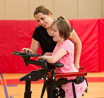 A therapist helps properly position a child in a dynamic gait trainer using a checklist