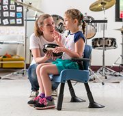 A child with autism sits in a Rifton compass chair to participate in music class.