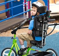 A boy riding on a Rifton Adaptive Tricycle