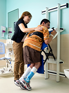 A young man using a Rifton Support Station with a caregiver assisting.